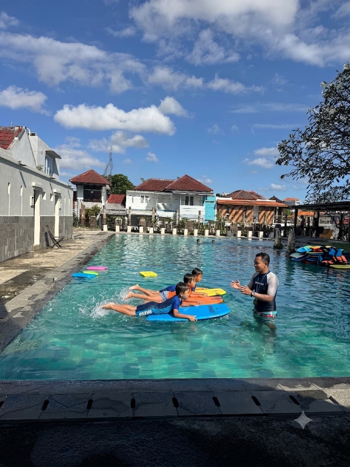 Children learning to swim with kickboards and a coach in the Jungle Kids pool