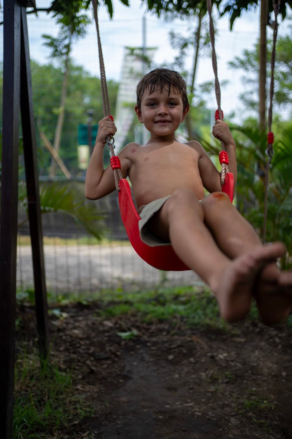 A boy swinging high on the red swing
